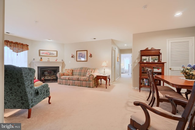 living area with a glass covered fireplace, recessed lighting, light colored carpet, and baseboards