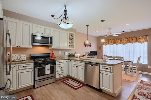 kitchen with stainless steel appliances, light wood-type flooring, a peninsula, a ceiling fan, and a sink