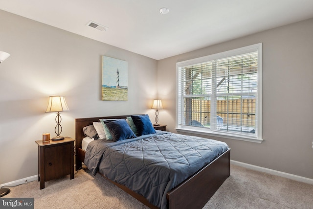 bedroom featuring baseboards, light carpet, and visible vents