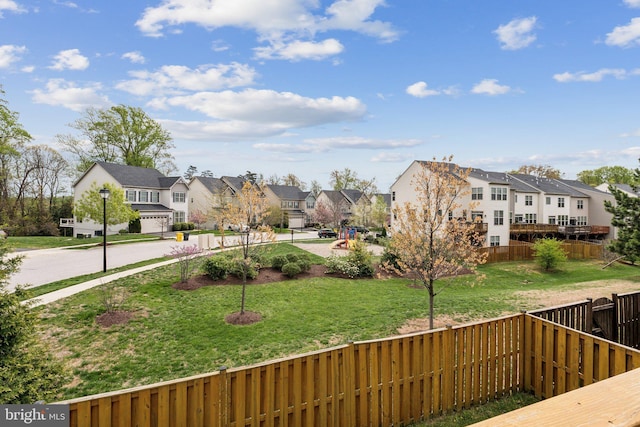 wooden deck with a lawn, fence, driveway, and a residential view