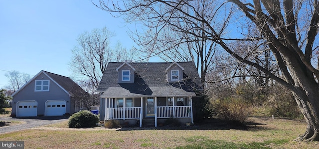 new england style home featuring a porch, a front lawn, a detached garage, and a shingled roof