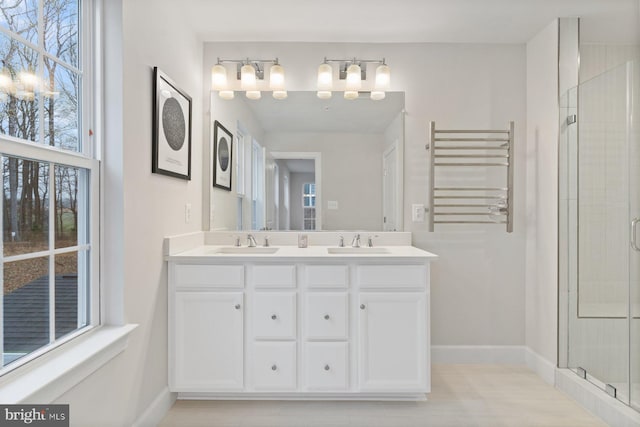 bathroom featuring a stall shower, double vanity, radiator heating unit, and a sink