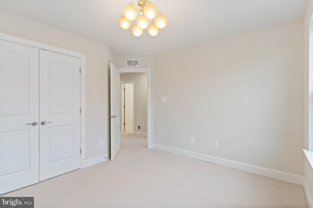 unfurnished bedroom with light colored carpet, visible vents, a notable chandelier, and baseboards