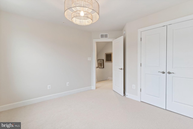 unfurnished bedroom with baseboards, visible vents, a closet, and light carpet
