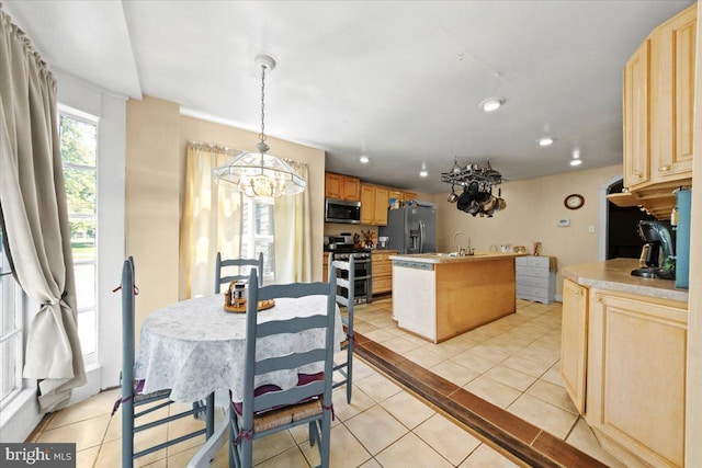 kitchen with a kitchen island with sink, stainless steel appliances, light brown cabinetry, and light tile patterned flooring
