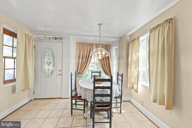 dining area with light tile patterned floors, baseboards, and a chandelier