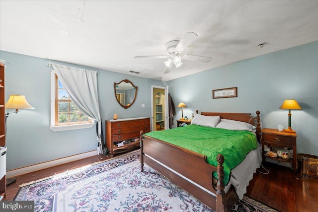 bedroom with baseboards, ceiling fan, visible vents, and wood finished floors