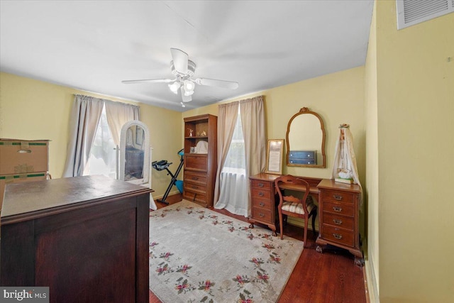 office area with baseboards, ceiling fan, wood finished floors, and visible vents