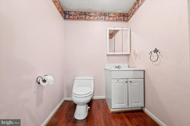 bathroom featuring baseboards, vanity, toilet, and wood finished floors