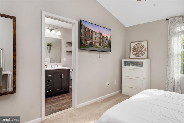 bedroom with light carpet, ensuite bathroom, baseboards, and a sink