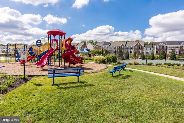 community playground with a residential view, fence, and a lawn