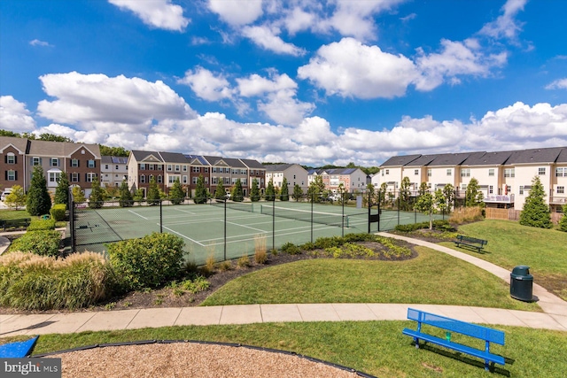 view of sport court featuring fence, a residential view, and a lawn