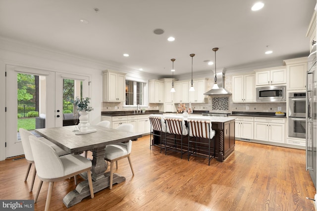 7521 Westfield Dr, Bethesda, MD 20817 - kitchen with appliances with stainless steel finishes, wall chimney range hood, a sink, a center island, and decorative backsplash