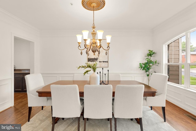 7521 Westfield Dr, Bethesda, MD 20817 - dining area featuring a decorative wall, crown molding, a chandelier, wood finished floors, and healthy amount of natural light