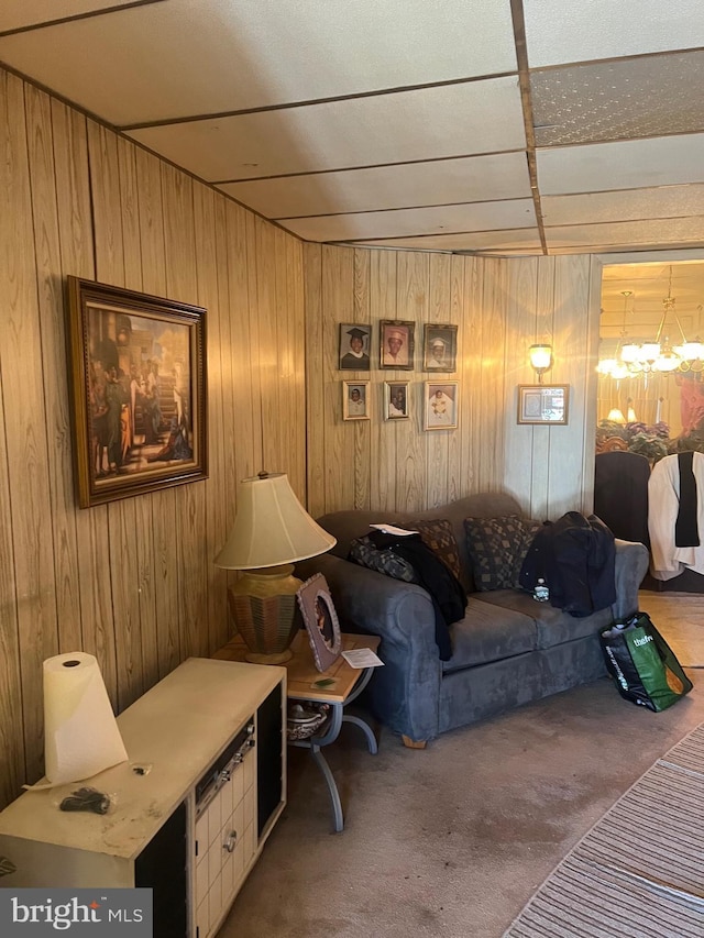 carpeted living room with a notable chandelier and wood walls