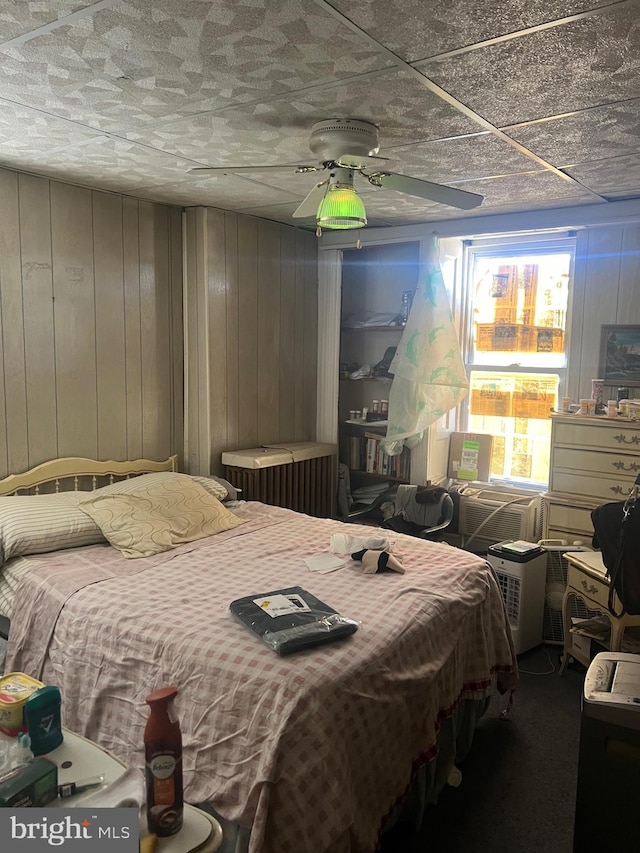 bedroom featuring wood walls and ceiling fan
