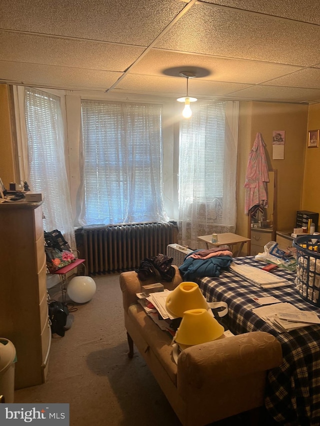 carpeted bedroom featuring radiator heating unit and a paneled ceiling