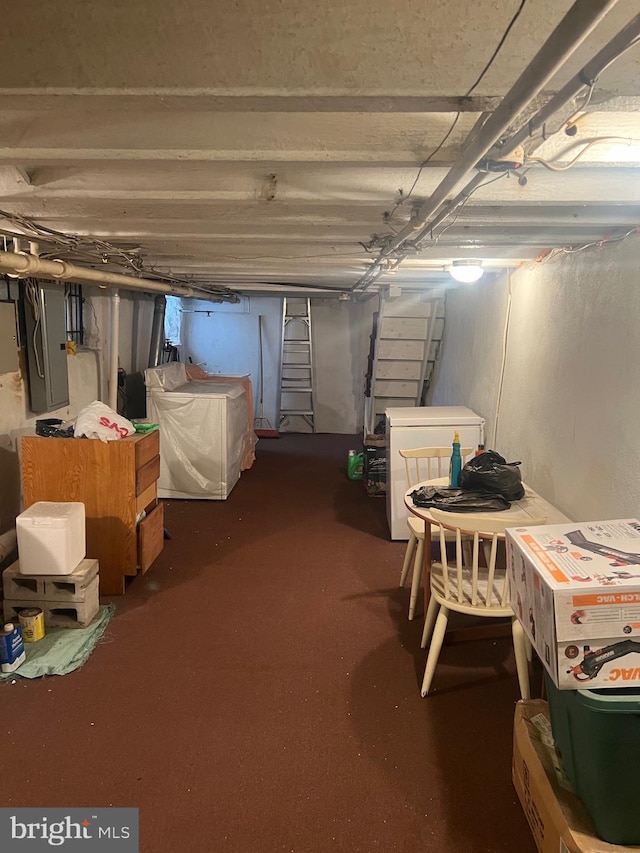 unfinished basement with refrigerator and electric panel