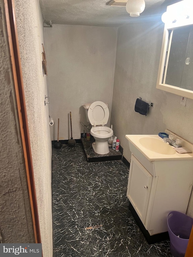 bathroom featuring a textured ceiling, toilet, and vanity