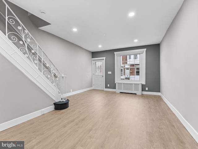 unfurnished living room with baseboards, wood finished floors, recessed lighting, and radiator