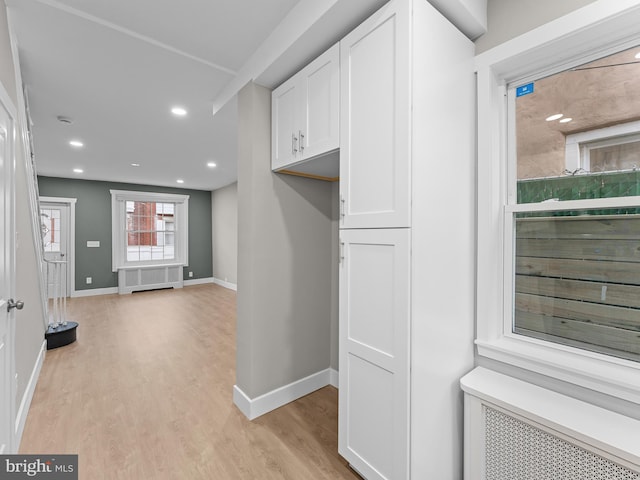 kitchen featuring baseboards, white cabinetry, light wood finished floors, and radiator heating unit