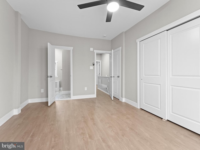 unfurnished bedroom with ensuite bath, baseboards, light wood-style floors, and ceiling fan