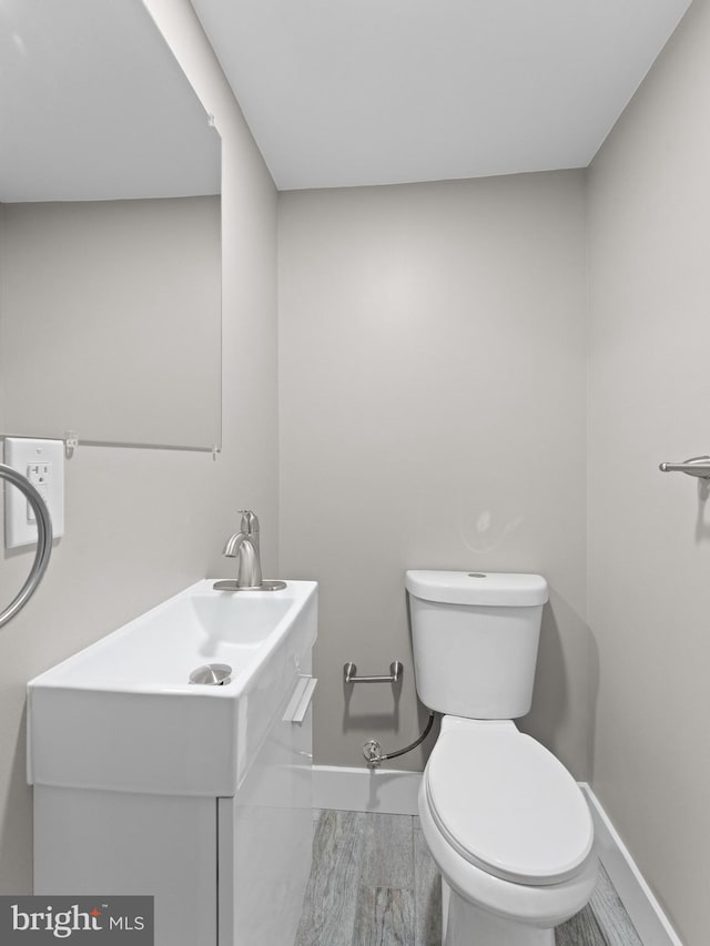 bathroom featuring baseboards, toilet, and vanity
