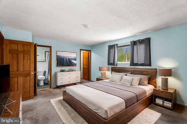 bedroom with carpet floors, a textured ceiling, and ensuite bath