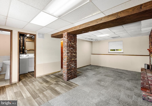 below grade area featuring a paneled ceiling, washing machine and dryer, and wood finished floors