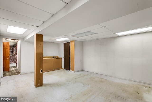 finished basement featuring light floors and a paneled ceiling