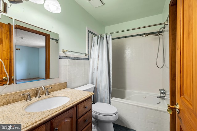 bathroom with tile walls, toilet, shower / bath combo with shower curtain, and vanity