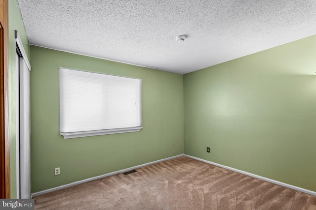 unfurnished room with carpet floors, a textured ceiling, and baseboards