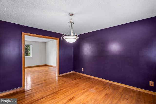 empty room featuring wood finished floors, baseboards, and a textured ceiling