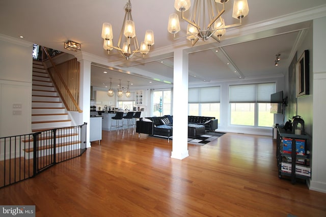 living area featuring an inviting chandelier, stairs, crown molding, and wood finished floors