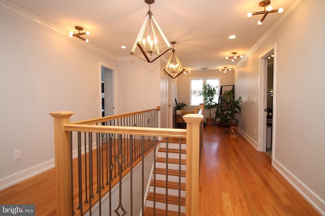 hall with an inviting chandelier, crown molding, and an upstairs landing