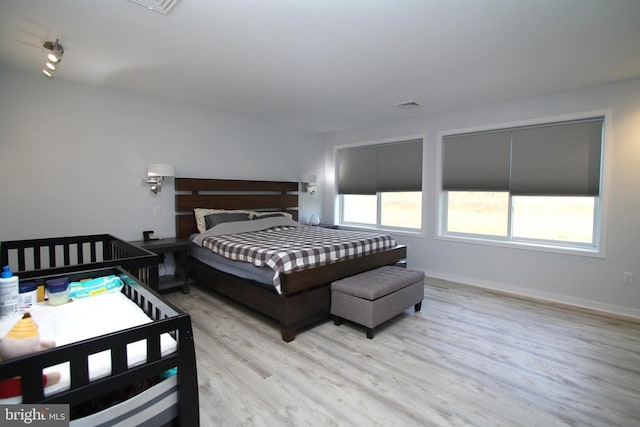 bedroom with baseboards, visible vents, and wood finished floors