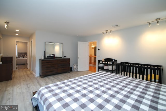 bedroom with track lighting, recessed lighting, wood finished floors, and visible vents