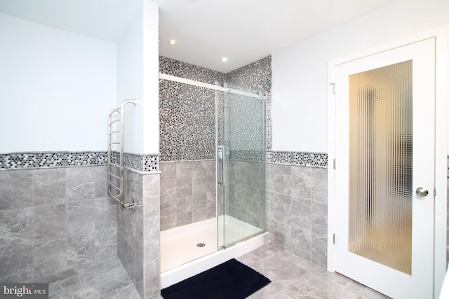 full bath featuring recessed lighting, wainscoting, a stall shower, and tile walls