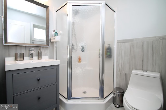 full bath with vanity, toilet, tile walls, and a stall shower