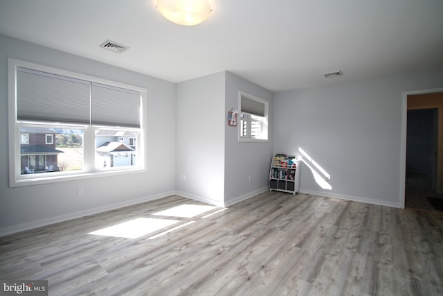 unfurnished room with baseboards, visible vents, and wood finished floors