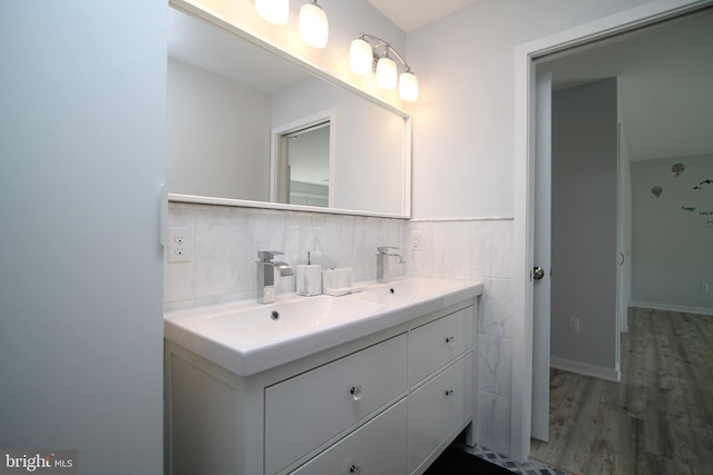 bathroom featuring double vanity, a sink, wood finished floors, and tile walls