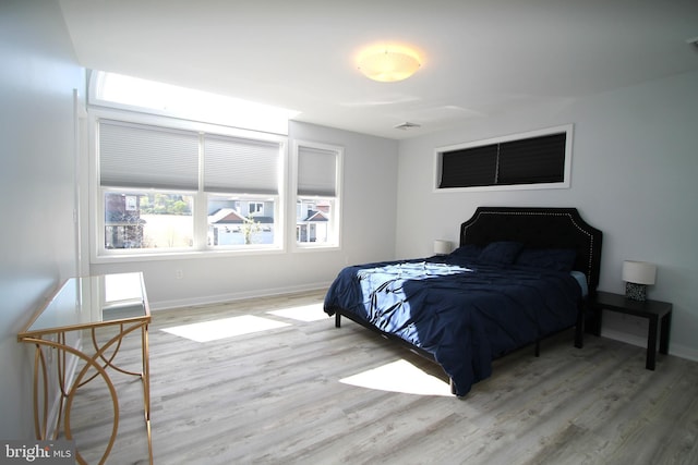 bedroom with baseboards, wood finished floors, and visible vents