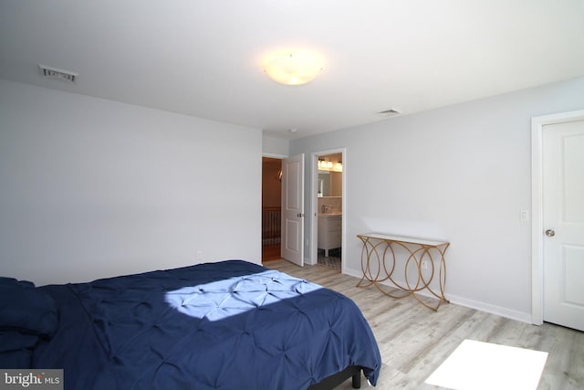 bedroom featuring baseboards, wood finished floors, and visible vents