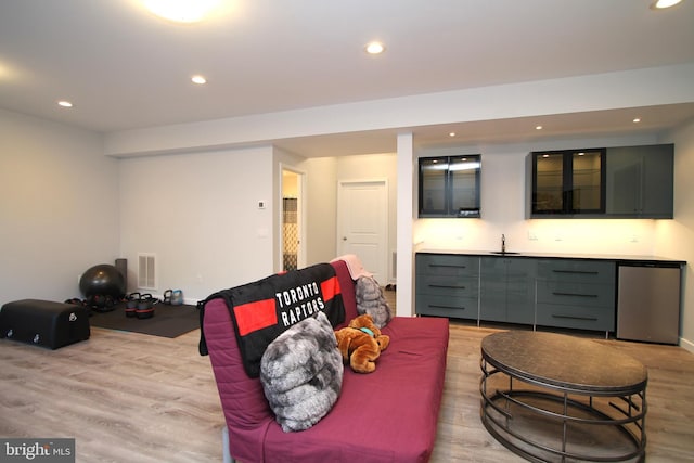living area featuring visible vents, baseboards, indoor wet bar, recessed lighting, and light wood-style flooring
