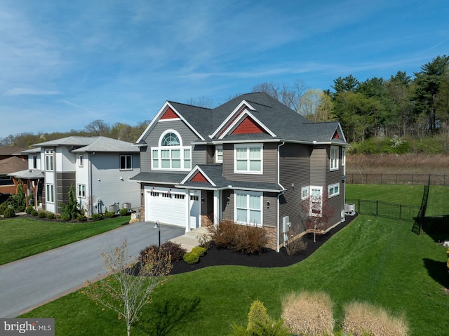 view of front of house with fence, an attached garage, a front yard, and aphalt driveway