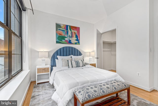 2412 17th St NW Unit 102, Washington, DC 20009 - bedroom with wood finished floors, multiple windows, baseboards, and a walk in closet