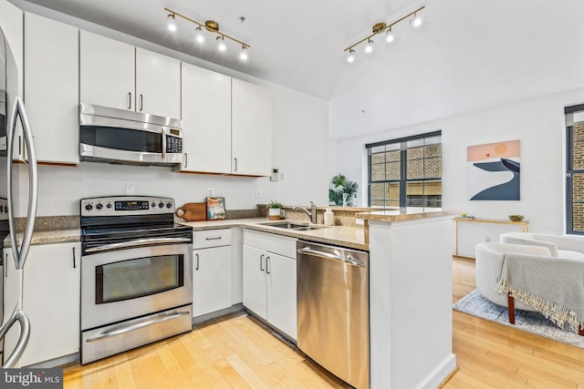 2412 17th St NW Unit 102, Washington, DC 20009 - kitchen featuring stainless steel appliances, a sink, a peninsula, light wood-type flooring, and white cabinetry