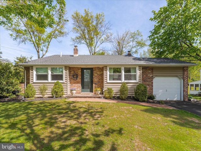 view of front of house with an attached garage, brick siding, a chimney, and a front yard