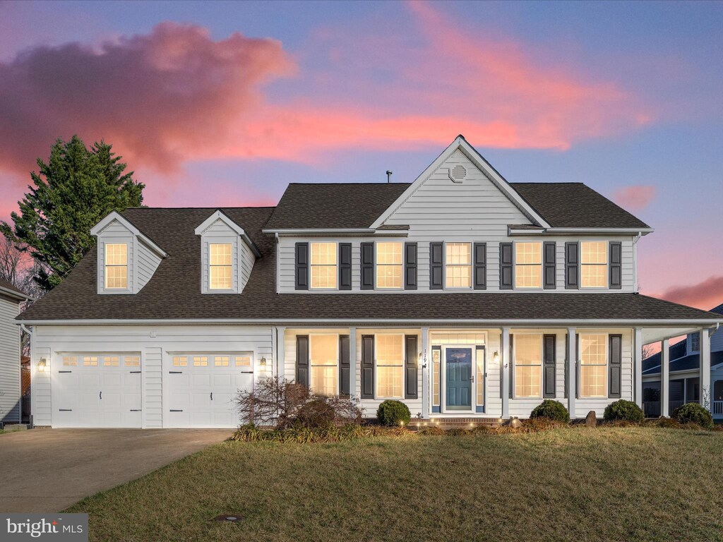 view of front of house featuring concrete driveway, a front lawn, a garage, a porch, and a shingled roof