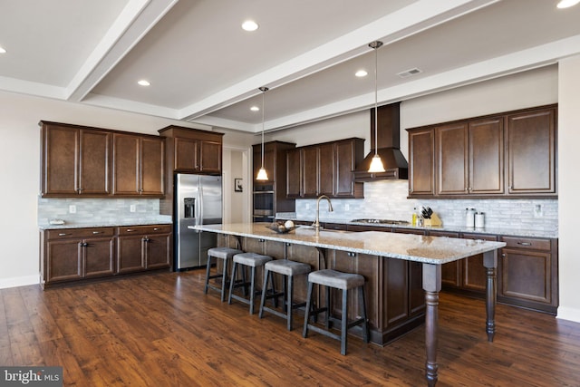 kitchen featuring beam ceiling, a sink, wall chimney exhaust hood, appliances with stainless steel finishes, and dark wood-style flooring